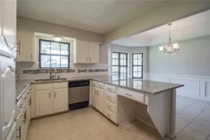 Bright kitchen with white cabinets, granite countertops, an island, and an adjacent dining area